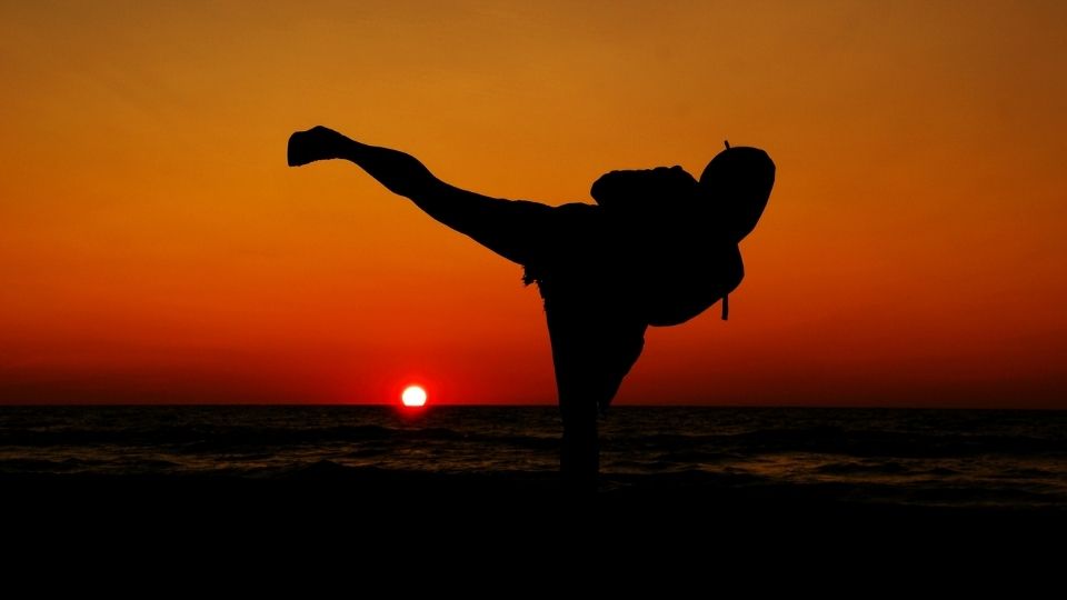 A martial artist practising kicks at sunset
