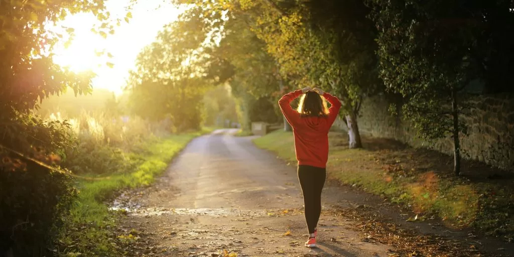 A girl walking down the road near the park