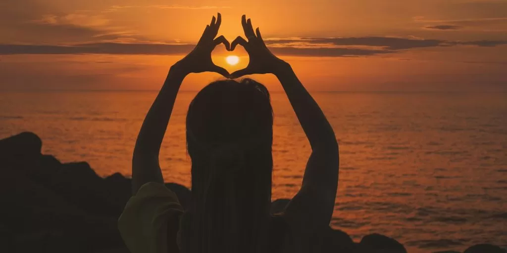 A woman making a heart gesture with her hands