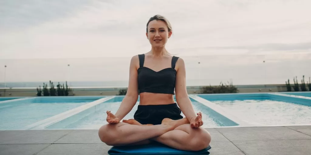 A woman meditating at the swimming pool