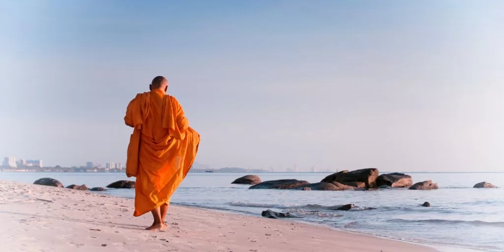 A monk walking down the beach