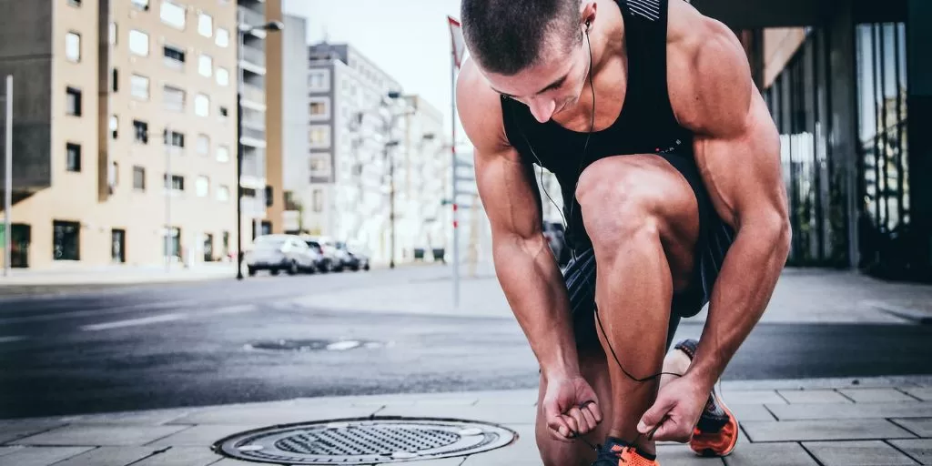 A muscular runner tying his shoe