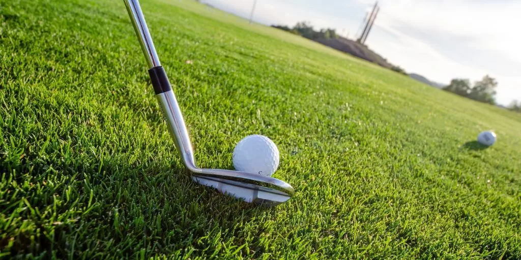 A picture of a golf club preparing to strike the ball