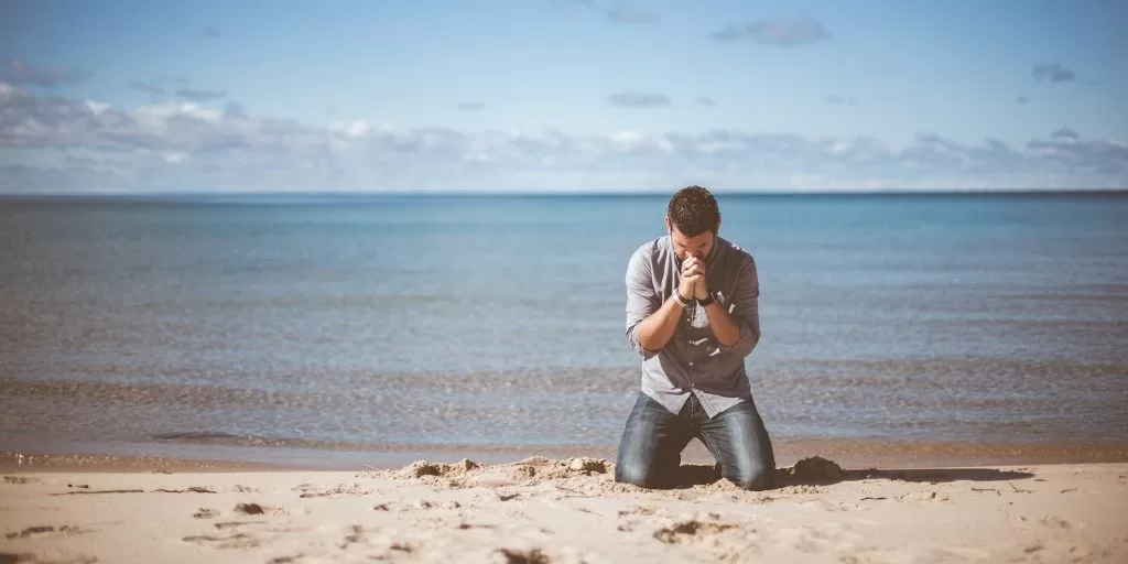 A man praying at the beach