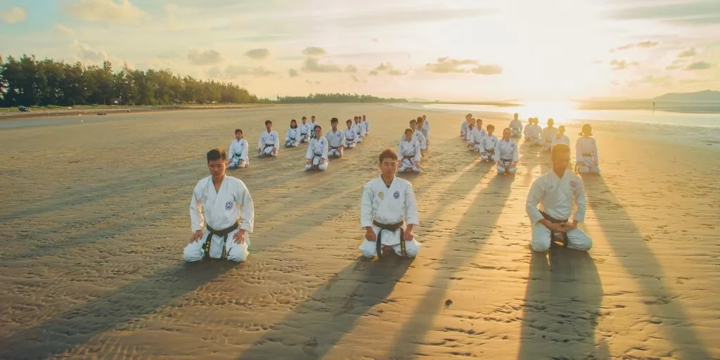 Martial artists meditating at the beach