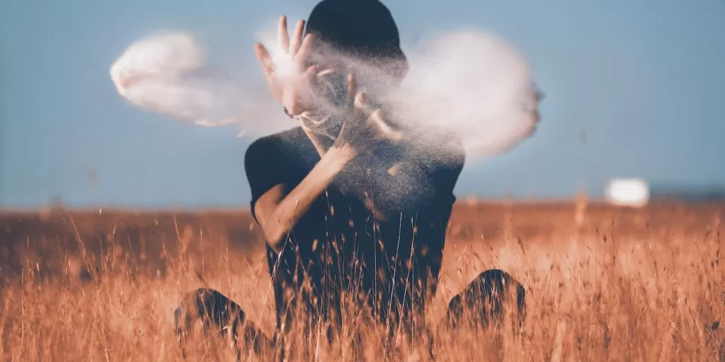 Meditating person sitting on the floor and throwing sand so it looks like they're casting a spell