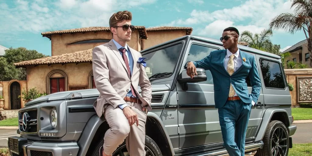 Mental coaching clientelle: 2 entrepreneurs wearing suits leaning on a car