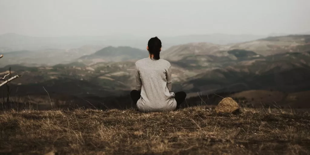 A woman meditating and observing the mountains