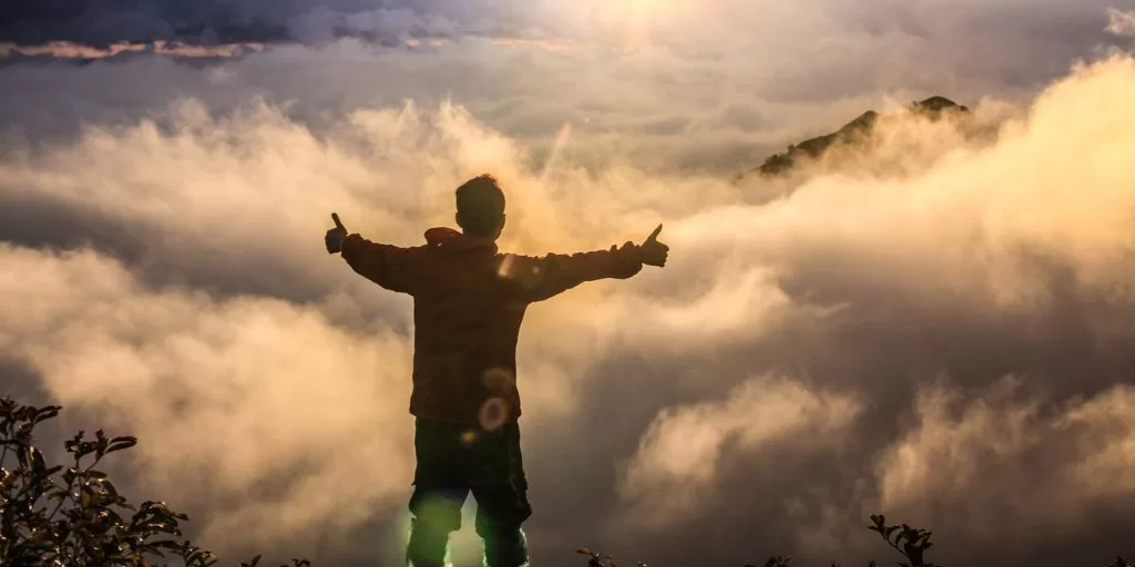 Man with a positive mindset standing on the top of a mountain