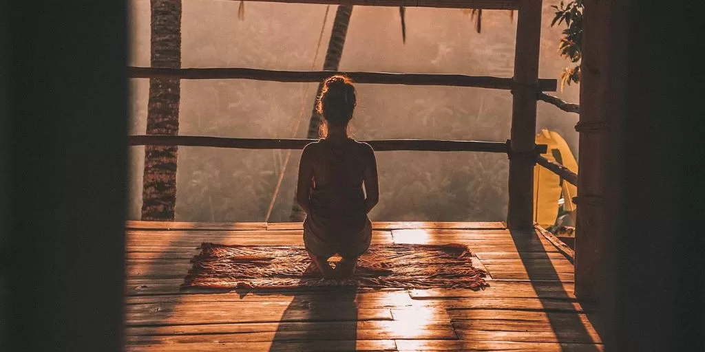 A woman meditating on the balcony at sunrise