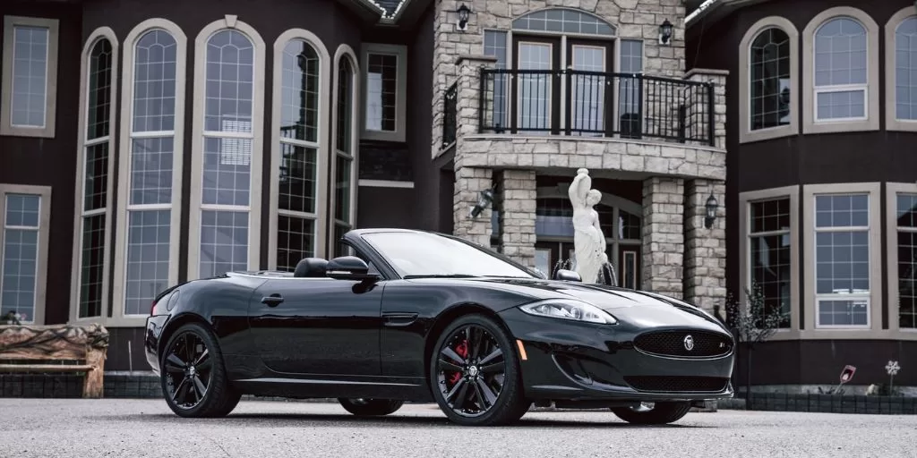 Expensive car standing in front of a large house