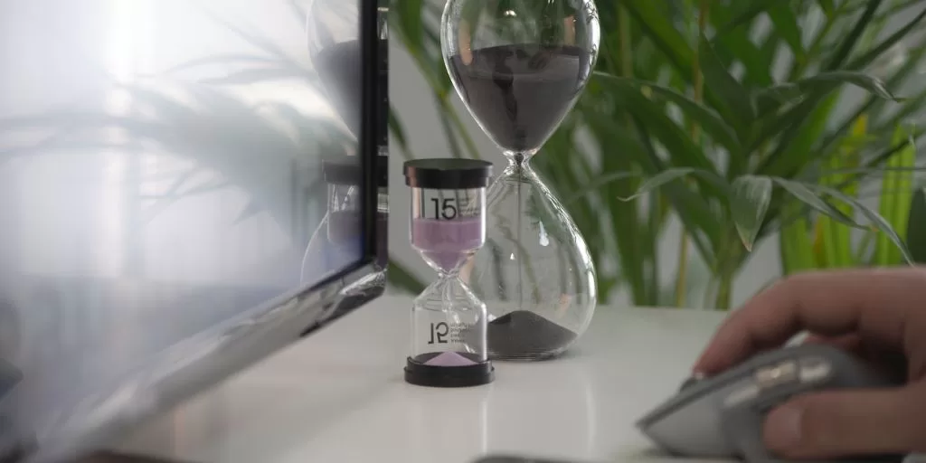Two hourglasses standing on the table by the computer screen