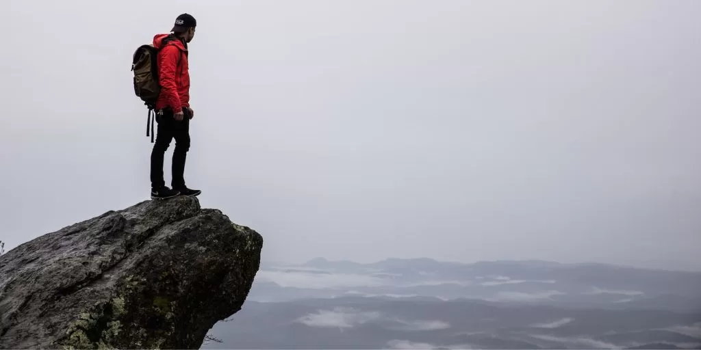 Victory: A hiker on the top of the mountain, looking down at the world