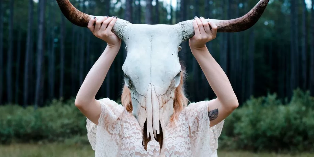 A woman holding up and worshipping a horned animal skull