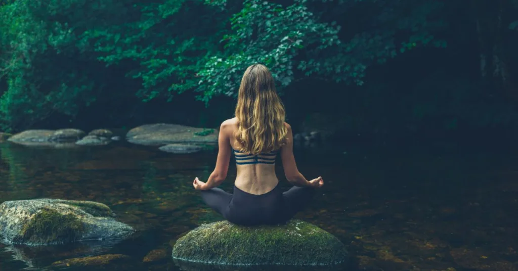 A woman sitting on a rock, practing mindfulness meditation