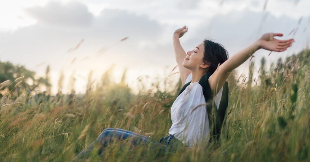 A happy and relaxed woman resting in a natural environment, breathing fully and deeply