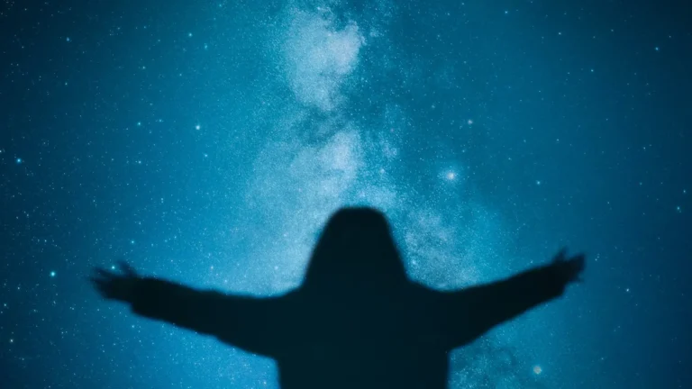 Reiki healer spreading her arms and welcoming healing cosmic energy under a starry sky