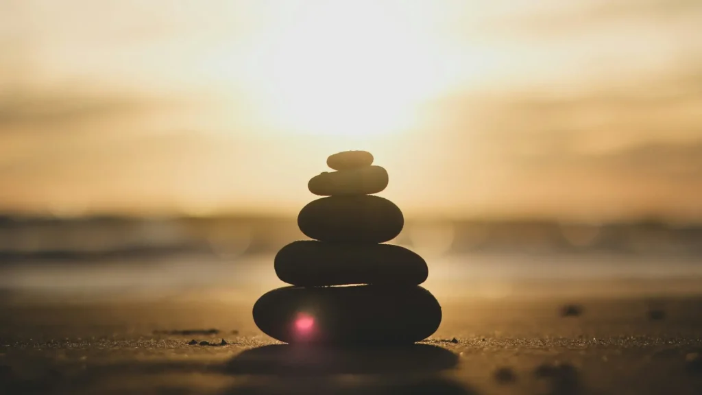 Stones on top of each other by the shore at the sunrise, symbolizing balance and harmony