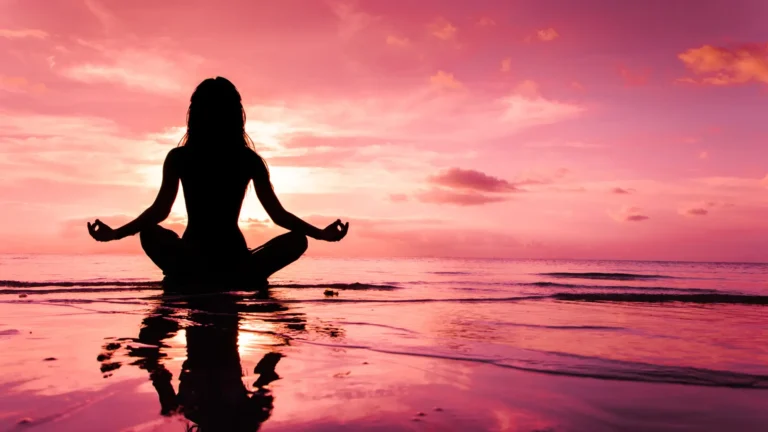 A woman meditating with chakras by the shore