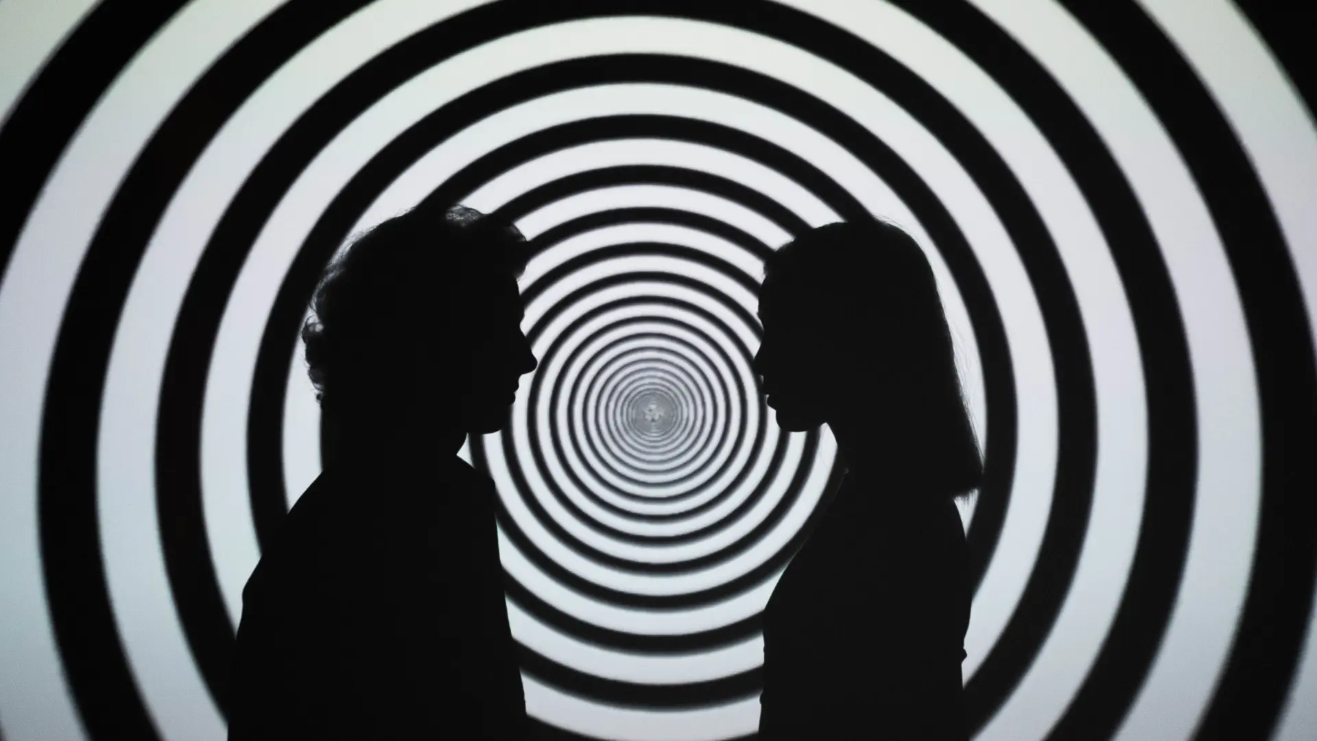 2 people standing in front of a hypnotizing background