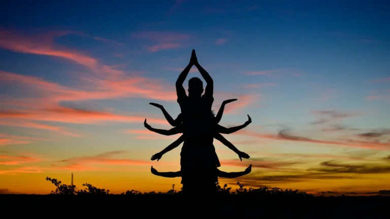 A group of people standing behind each other with arms spread out wide, resembling the Shiva goddess silhouette