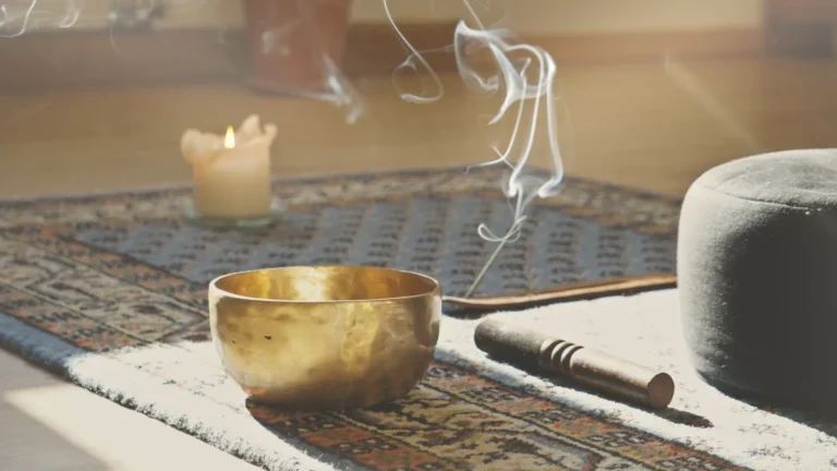 A singing bowl and a lit incense stick on the floor